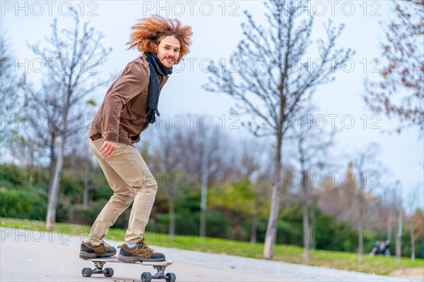 Skater with curly redhead hair on a board in an urban park