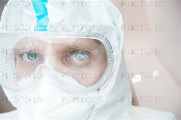 Medical laboratory assistant in a chemical protection suit and safety glasses