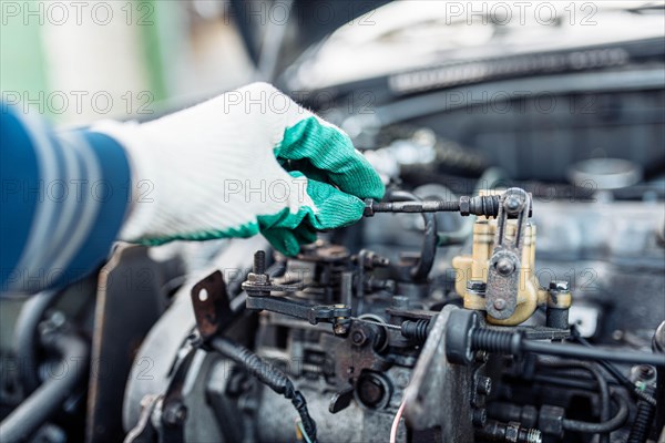 Auto mechanic regulates fuel supply with throttle cable lever