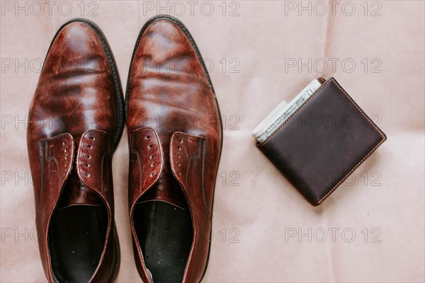 Brown men's shoes made of genuine leather and a brown leather wallet with money