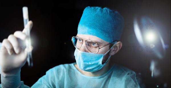 Scientist doctor in a dark laboratory with a test tube of a medicinal product