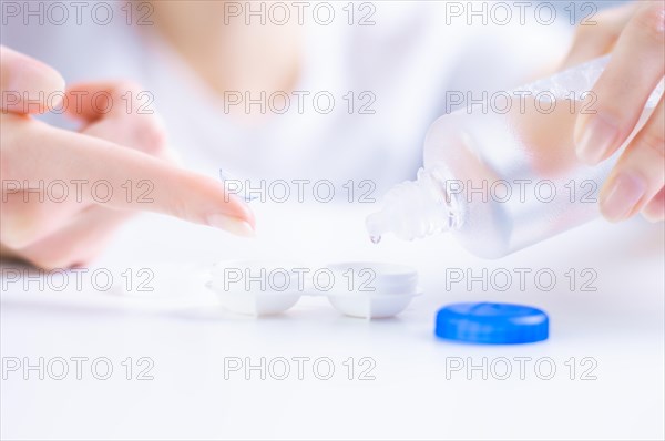 Woman pours liquid on a lens for the eyes. Ophthalmology concept.