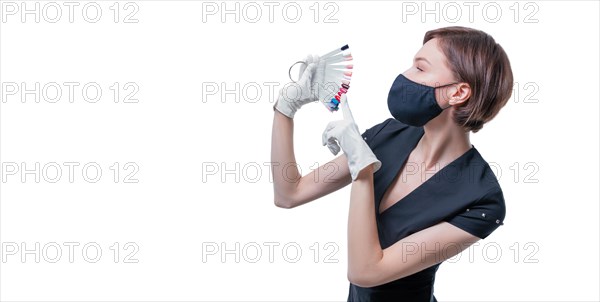 Portrait of an elegant beautiful girl wearing a protective mask with a set of nail palette in hand. White background. Advertising banner for beauty salons during Covid-19. Pandemic. Modern trends.
