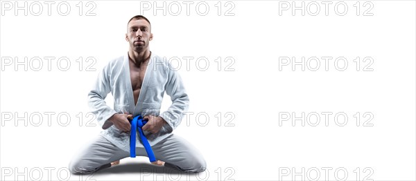 Athlete in a kimono with a blue belt sits and waits for the opponent. Concept of karate