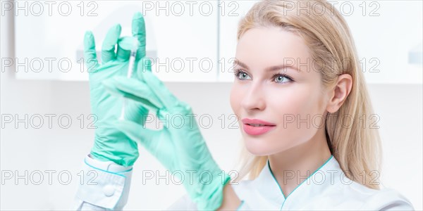 Portrait of a blonde girl in a medical gown with a syringe in her hands. Vaccination concept.