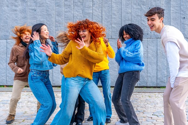 Frontal view of a happy girl dancing with a group of friends in the city