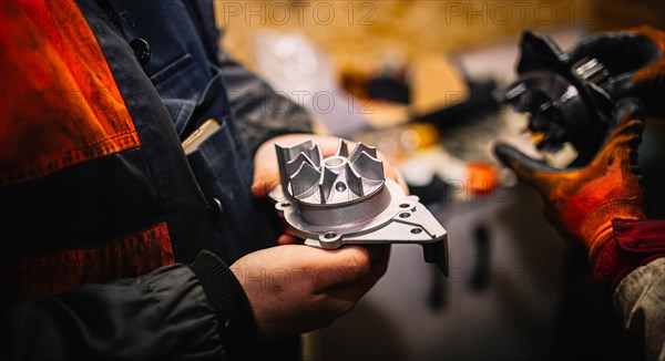 Automotive water pump of the engine cooling system in the hands of an auto mechanic