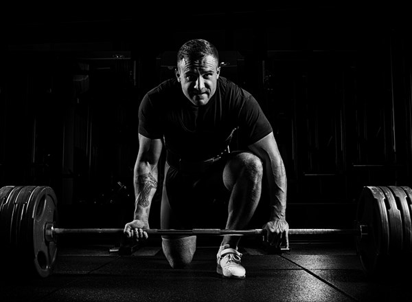 Professional athlete bent over the barbell and is preparing to lift a very heavy weight. Front view