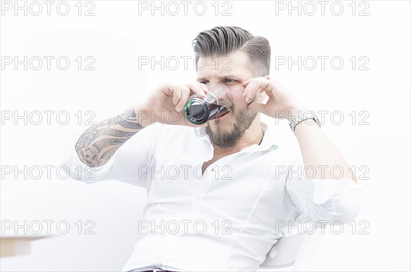 Stylish man sits on a chair and gets drunk with rum and cola. The concept of unsuccessful business
