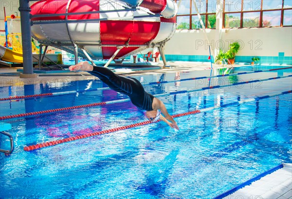 Professional athlete jumps into the water in the pool from the platform