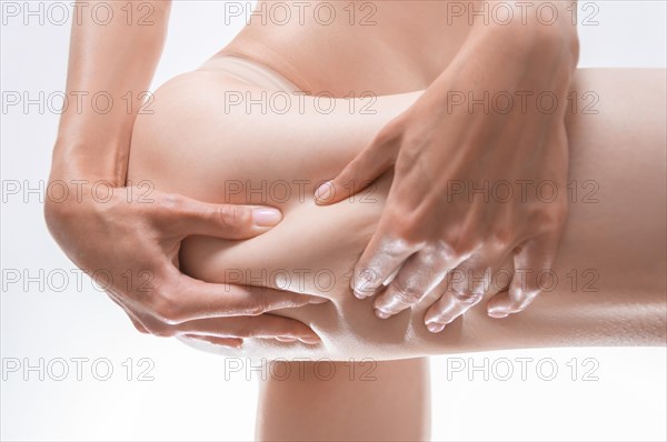 Image of a woman squeezing the skin on her thigh. Cosmetic concept.