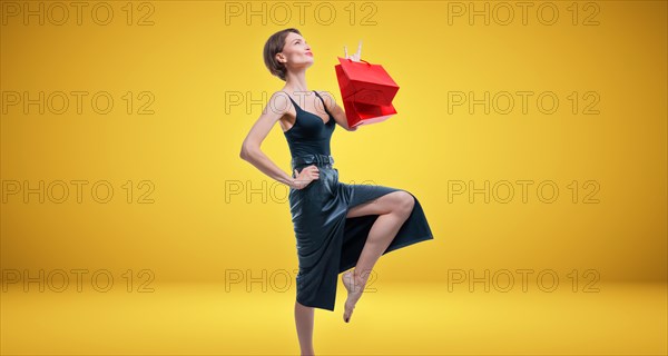 Stylish adult tall woman posing in studio with gift bags. Shopping concept. Shopping centers.