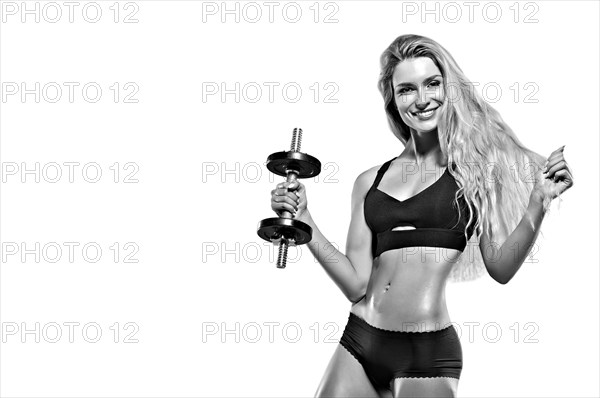 Beautiful athlete posing with a dumbbell in the studio.