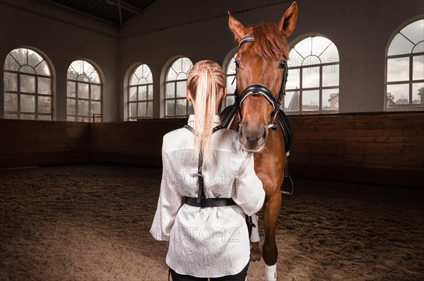 Image of a blonde woman in the form of a rider from the back. Horse racing and equestrian sport concept.