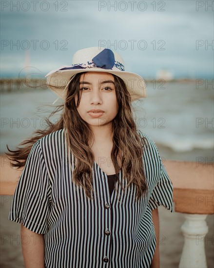 Portrait of attractive woman in hat on the pier looking at camera. Portrait of young tourist woman in hat on a pier