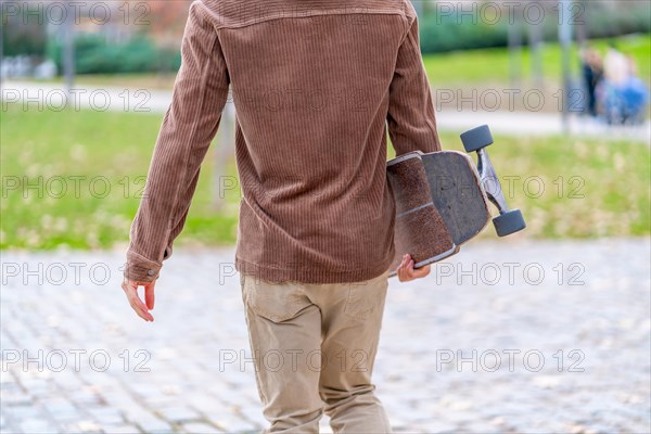 Rear view of an unrecognizable skater walking to an urban park