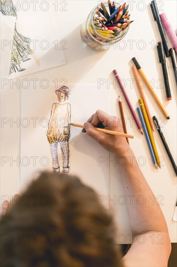 Top view of a fashion designer drawing a fashion sketch. Vertical shot