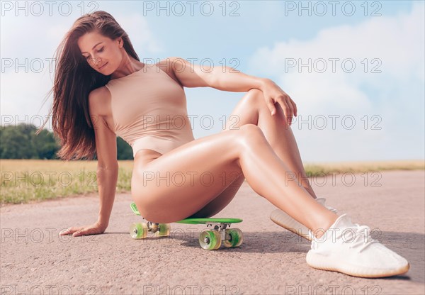 Image of a sexy girl in a bodysuit with a skateboard. Sports concept.