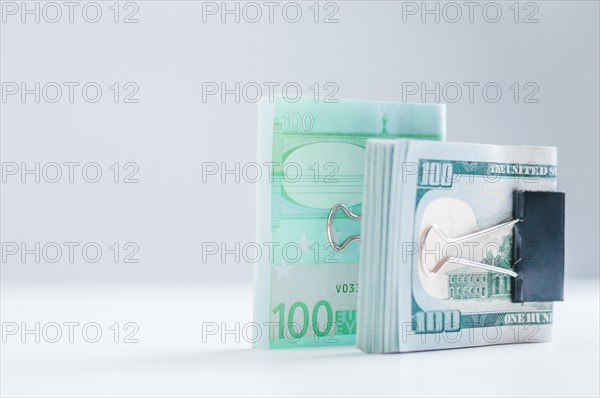 Packs of euros and hundred-dollar bills lie on a white table fastened with paperclips. The concept of savings during the crisis. Dollars vs Euros.