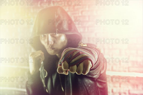 Boxer in a black sweatshirt and bandages wound on his hands beats his fist forward. The concept of sports