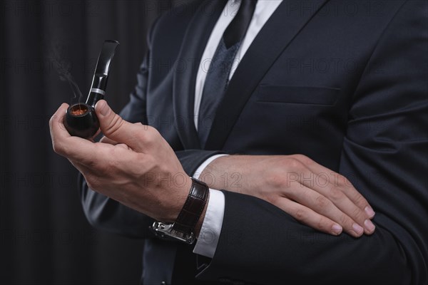 Image of male hands holding a smoking pipe. Tobacco smoking concept.