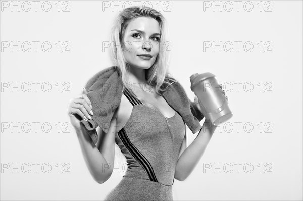 Charming model posing in the studio with a shaker in her hands and a towel around her neck.