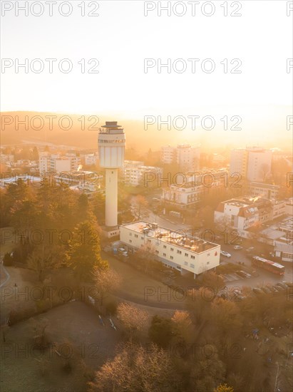 Aerial view of the water tower in the morning light of sunrise with the city skyline in the background