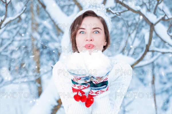 Portrait of a beautiful woman against the background of a winter forest in New Year's mittens. Concept of Christmas