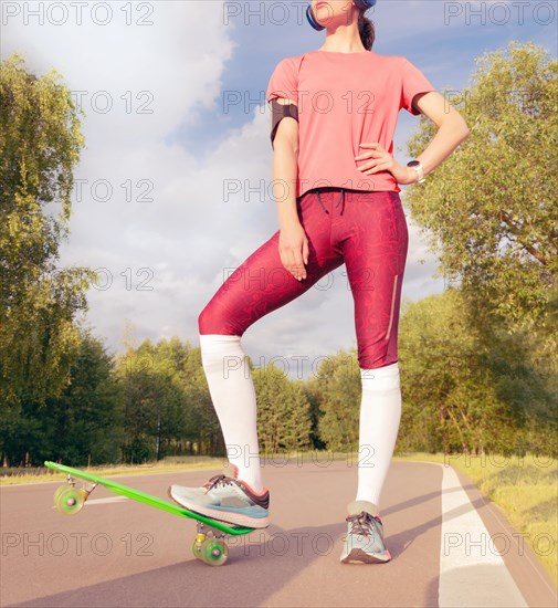 Image of a girl standing near a skateboard in the park. Sports concept.