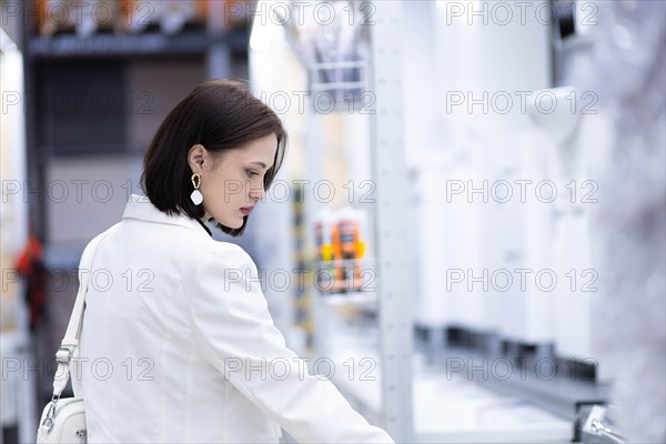 Beautiful young woman in a white jacket chooses plumbing supplies in a hardware store
