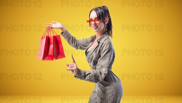 Business woman with red shopping bags. Yellow background. Holiday shopping concept.