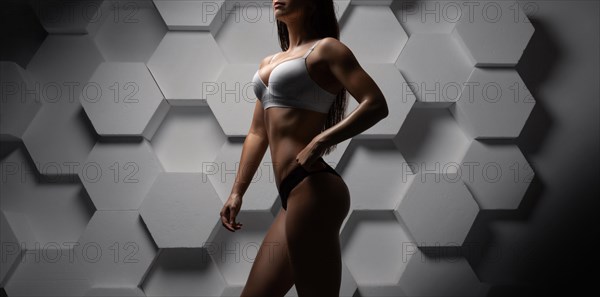 Tall adult woman with beautiful hair posing in sportswear. Fitness and bodybuilding concept.