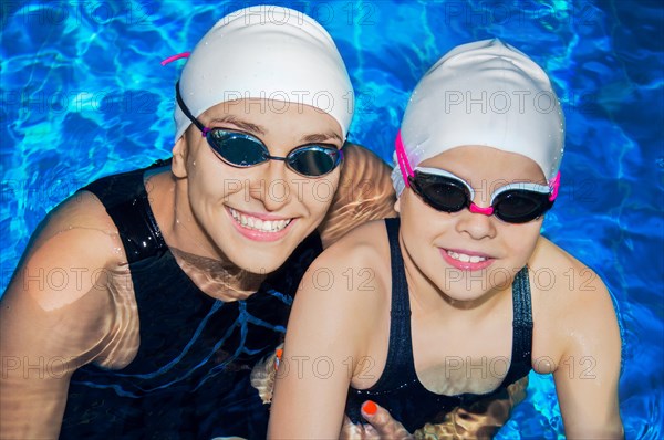 Charming coach with his student swimming in the pool and smiling