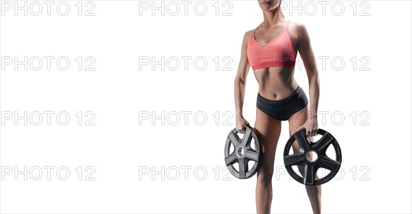 Delightful athlete posing in the studio with weights in her hands. The concept of sports