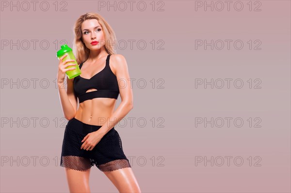 Charming girl with shaker in hands posing in studio.