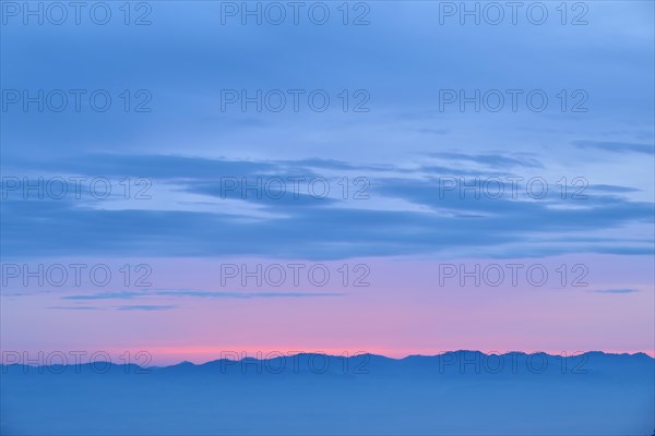 Dawn with pink and blue colours over a mountainous silhouette