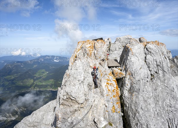 Female mountaineer climbing a via ferrata secured with a steel cable