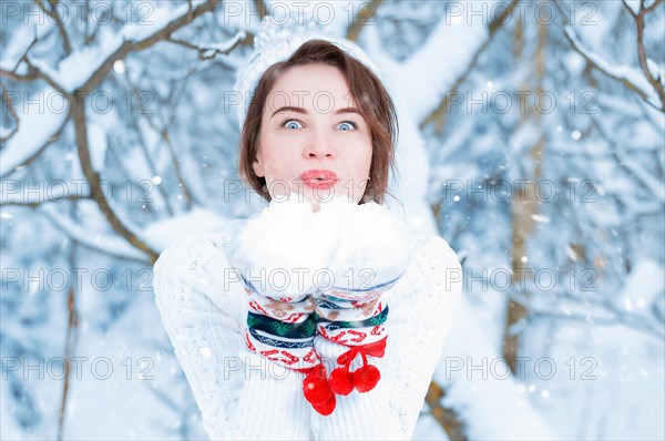 Portrait of a beautiful woman against the background of a winter forest in New Year's mittens. Concept of Christmas