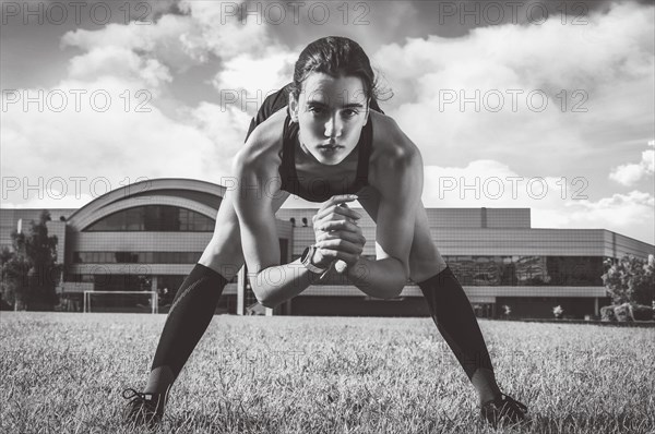 Beautiful young runner warms up on the soccer field before the race. Sports concept.