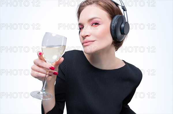 Portrait of a woman in professional headphones with a glass of wine in her hand. White background. Dj concept.