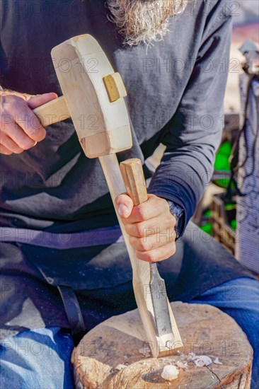 Craftsman working with wood at a street market at his stall of handmade wooden items