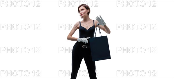 Stylish tall girl in white gloves demonstrates a black luxury package. The concept of safe shopping during a pandemic.