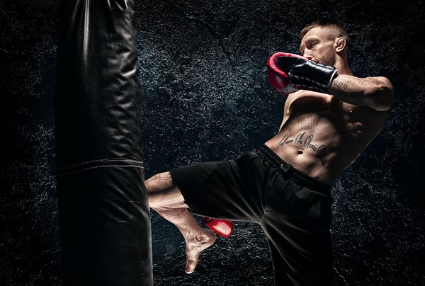 Kickboxer hits the bag with his knee. Training a professional athlete. The concept of mma