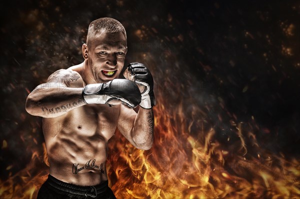 Mixed martial artist posing against the backdrop of fire and smoke. Concept of mma