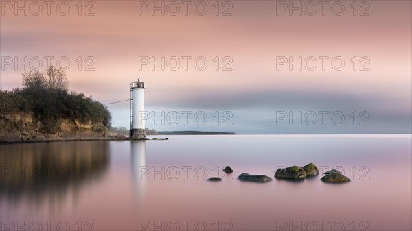 Long exposure of a colourful sunset behind the abandoned lighthouse on the Baltic Sea coast in Maltzien on Ruegen