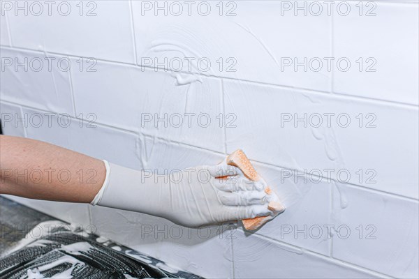 Cleaning ceramic tiles at home with a cleaning agent in a glove