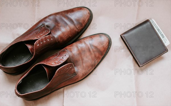 Brown men's shoes made of genuine leather and a brown leather wallet with money