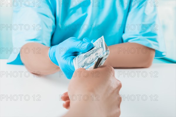 The girl gives the doctor a pack of hundred-dollar bills. Medicine concept.