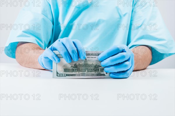 Doctor holds one hundred dollar bills. The concept of corruption in medicine.