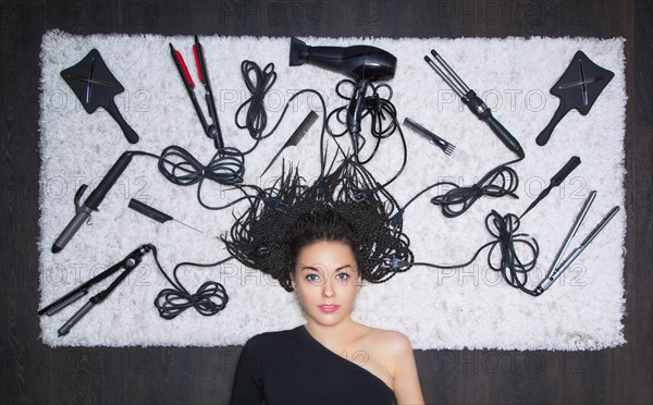 Charming girl lies on a snow-white soft carpet. Around there are hairdresser's accessories